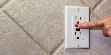 Hand pressing reset button on GFCI outlet not working.